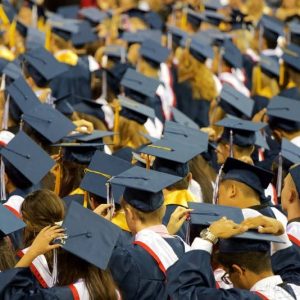 College graduates stand in caps and gowns during a commencement ceremony.