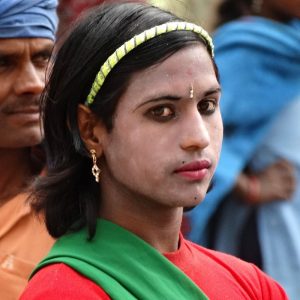 A hijra dancer with a feminine appearance wearing eyeliner, lipstick, and earrings.