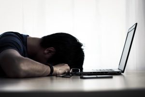 man sleeping with his head down on a table